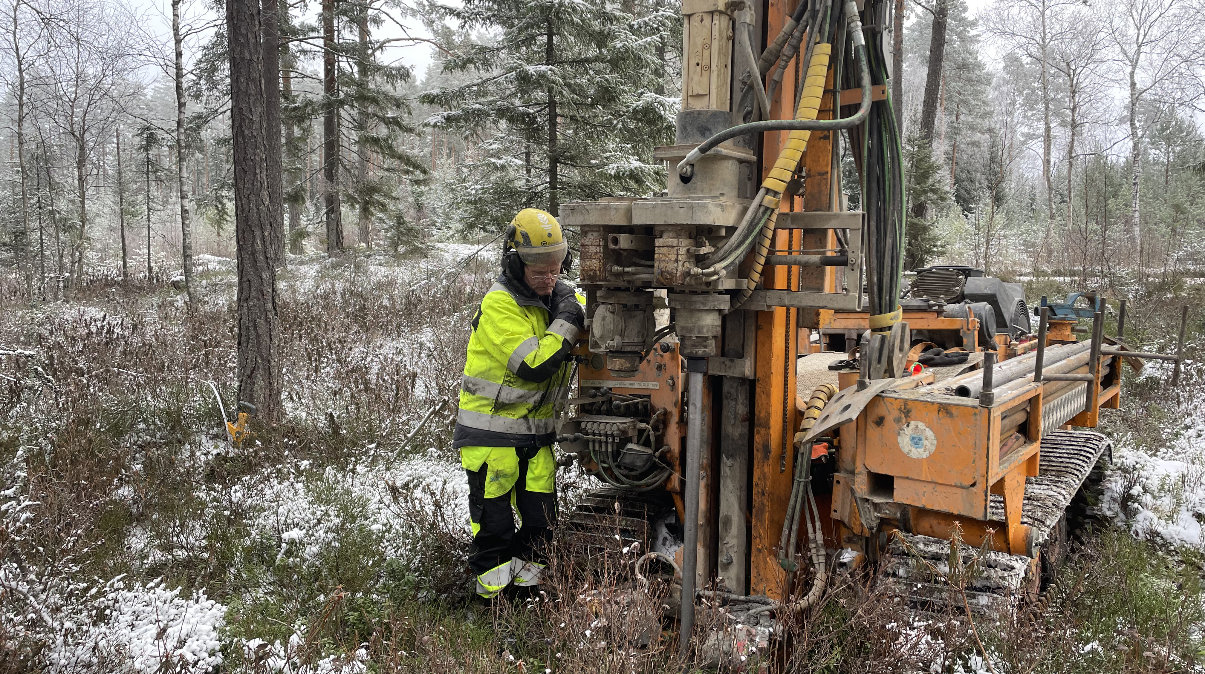 Person i skyddskläder vid en borrbandvagn i naturen. Person i skyddskläder vid en borrbandvagn i naturen.
